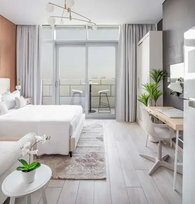 a bedroom with a white bed and a desk and a table at Silkhaus renovated studio with Burj Khalifa view in DIFC in Dubai
