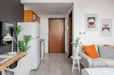 a small apartment with a white refrigerator and a couch at Silkhaus renovated studio with Burj Khalifa view in DIFC in Dubai
