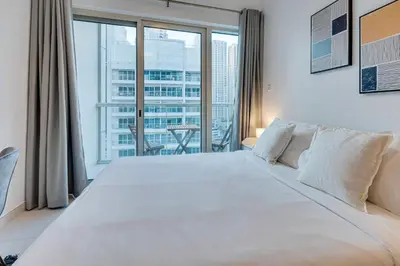 a bedroom with a large white bed with a large window at Great views from New apartment in Dubai Marina in Dubai