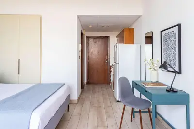 a bedroom with a bed and a desk and a refrigerator at Silkhaus elegant studio with Burj Khalifa view and balcony in Dubai