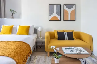 a bedroom with a bed and a yellow couch at Silkhaus modern furnished studio in DIFC center with balcony in Dubai