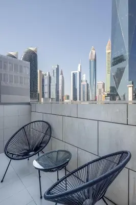 two chairs and a table on a balcony with a city skyline at Silkhaus modern furnished studio in DIFC center with balcony in Dubai