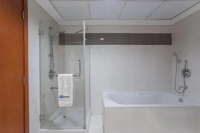 a bathroom with a shower and a tub and a sink at HiGuests - Luxury Apartment in the Iconic Park Towers in Dubai