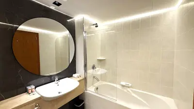 a bathroom with a sink and a mirror and a tub at Trinity Holiday Homes - Sheikh Zayed Road Right Next to Financial Center Metro Station Exit 1 in Dubai