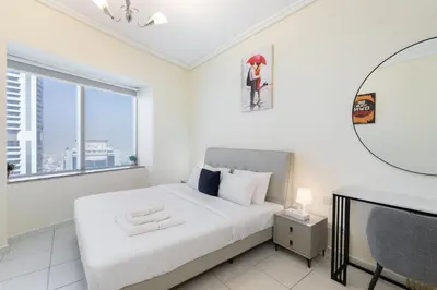 a white bedroom with a bed and a desk at Trinity Holiday Homes - Sheikh Zayed Road Right Next to Financial Center Metro Station Exit 1 in Dubai