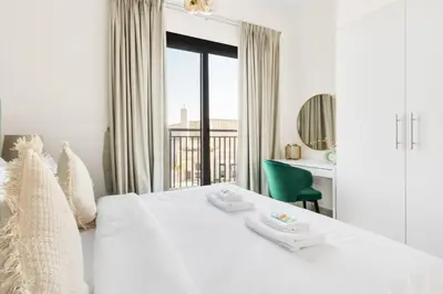 a white bedroom with a white bed and a window at GuestReady - The Wandering Oasis in Town Square in Dubai