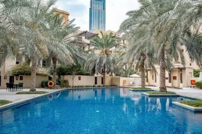 a large swimming pool with palm trees and a building at Newly furnished. Cozy apartment. Quite location. in Dubai