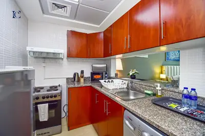 a kitchen with wooden cabinets and a counter top at Luxury Escapes - New Lake View Studio in JLT - near Metro in Dubai