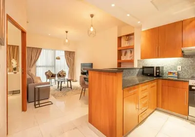 a kitchen with a counter and a living room at Hometown Apartments - Cosy 1 Br Apartment with Brand New Furniture in DIFC in Dubai