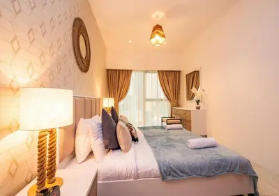 a bedroom with a bed and a lamp and a window at Hometown Apartments - Cosy 1 Br Apartment with Brand New Furniture in DIFC in Dubai
