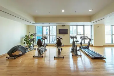 a gym with several tread machines in a room with windows at Full Marina and Ain Dubai Wheel View 1BR at The Point Dubai Marina by Deluxe Holiday Homes in Dubai