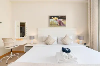a white bedroom with a white bed and a chair at Welcoming 1 Bedroom Palm Jumeirah with sea View in Dubai