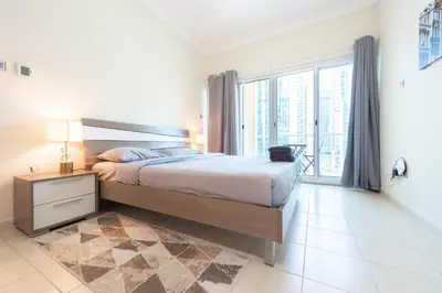 a bedroom with a large bed and a large window at Luxury Escapes - Elegant and spacious 1bed with 2 balconies in JLT in Dubai
