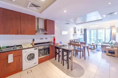 a kitchen with a washer and a table and chairs at Luxury Escapes - Elegant and spacious 1bed with 2 balconies in JLT in Dubai