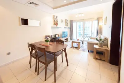 a dining room and living room with a table and chairs at Luxury Escapes - Elegant and spacious 1bed with 2 balconies in JLT in Dubai