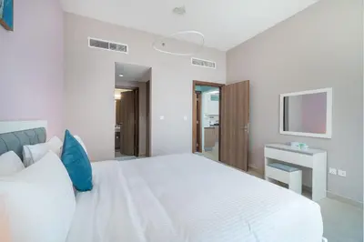 a bedroom with a white bed and a television at Trinity Holiday Homes - Spacious Modern Living 1BR & 2BR Unique Apartment in Dubai