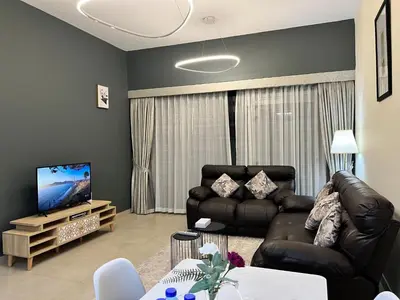 a living room with two leather couches and a tv at Trinity Holiday Homes - Spacious Modern Living 1BR & 2BR Unique Apartment in Dubai