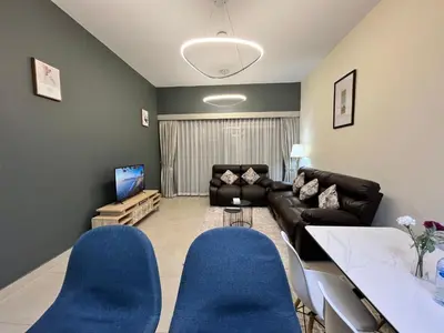 a living room with a black couch and blue chairs at Trinity Holiday Homes - Spacious Modern Living 1BR & 2BR Unique Apartment in Dubai