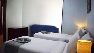 a room with two beds and a blue chair at Signature Hotel Apartments and Spa in Dubai