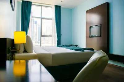 a bedroom with a bed and a chair and a window at Signature Hotel Apartments and Spa in Dubai
