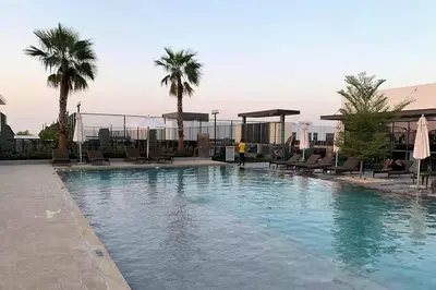 a large swimming pool with chairs and palm trees at Upgraded spacious 3BR+Maid Villa in Dubai