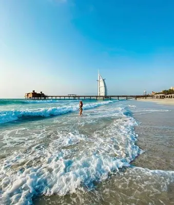 a person standing in the water at the beach at Luxury Room with Marina view close to JBR Beach and Metro with Shared Kitchen in Dubai