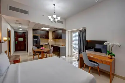 a bedroom with a bed and a desk and a kitchen at Regency Luxury Suites in Dubai
