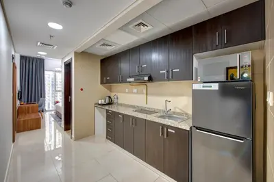 a kitchen with wooden cabinets and a stainless steel refrigerator at Regency Luxury Suites in Dubai