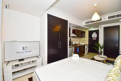 a bedroom with a bed and a tv in a room at Luxury Escapes - Cozy Studio with Balcony near Metro - Goldcrest 2 JLT in Dubai