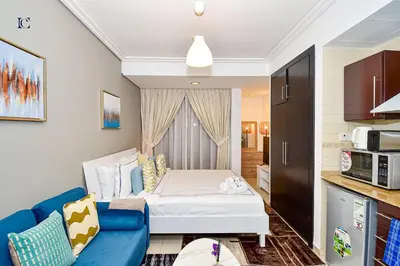 a small room with a bed and a blue couch at Luxury Escapes - Cozy Studio with Balcony near Metro - Goldcrest 2 JLT in Dubai