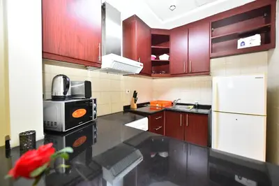 a kitchen with wooden cabinets and a white refrigerator at Luxury Escapes - Budget-Friendly Studio Near Metro - MED67 DG in Dubai