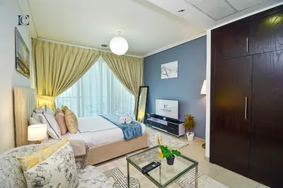 a bedroom with a bed and a tv and a couch at Brand New Studio Apt - Near JLT Metro in Dubai