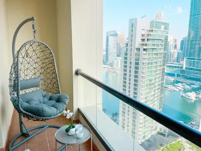 a swing chair on a balcony with a view of the city at Apartments on JBR by HAPPY SEASON in Dubai