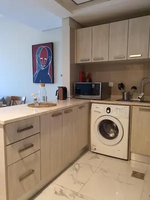 a kitchen with a washing machine and a microwave at Cozy 1-bedroom apartment in Dubai South with Pool in Dubai