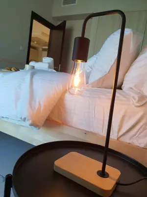 a lamp on a table in front of a bed at Cozy 1-bedroom apartment in Dubai South with Pool in Dubai