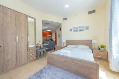 a large bedroom with a bed and a kitchen at Luxury Escapes - Modern Budget studio with balcony in JLT! in Dubai