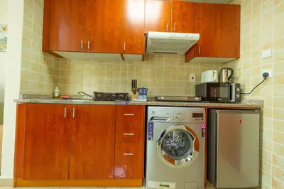 a kitchen with a washing machine and wooden cabinets at Luxury Escapes - Modern Budget studio with balcony in JLT! in Dubai