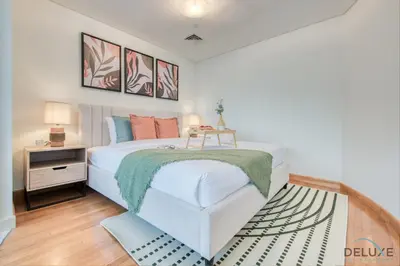 a bedroom with a large white bed and a table at Charming Studio at Sky Gardens DIFC by Deluxe Holiday Homes in Dubai