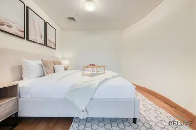 a bedroom with a white bed with a table on it at Special Rate Cozy Studio with Balcony Near Attractions by Deluxe Holiday Homes in Dubai