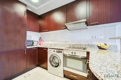 a kitchen with wooden cabinets and a dishwasher at Calm Studio at Sky Gardens DIFC by Deluxe Holiday Homes in Dubai