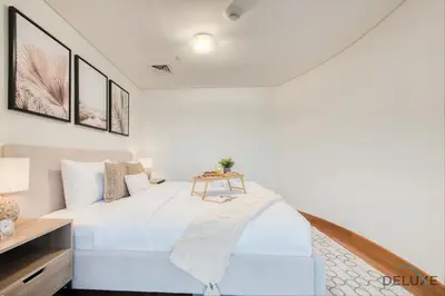 a white bedroom with a bed and a table at Calm Studio at Sky Gardens DIFC by Deluxe Holiday Homes in Dubai