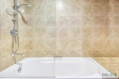 a bathroom with a shower and a white tub at Oceanic Studio at Sky Gardens DIFC by Deluxe Holiday Homes in Dubai