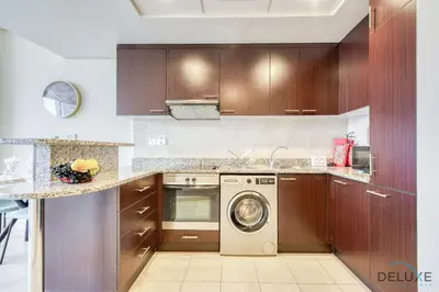 a kitchen with wooden cabinets and a washing machine at Oceanic Studio at Sky Gardens DIFC by Deluxe Holiday Homes in Dubai