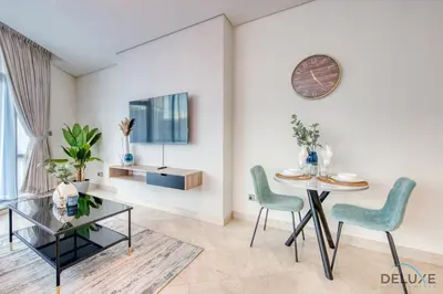 a living room with a table and chairs and a clock at Tranquil Studio at Sky Gardens DIFC by Deluxe Holiday Homes in Dubai