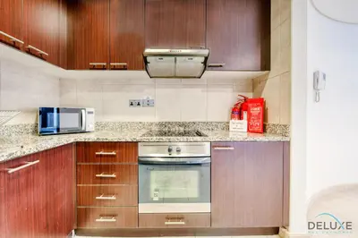 a kitchen with wooden cabinets and a microwave at Tranquil Studio at Sky Gardens DIFC by Deluxe Holiday Homes in Dubai