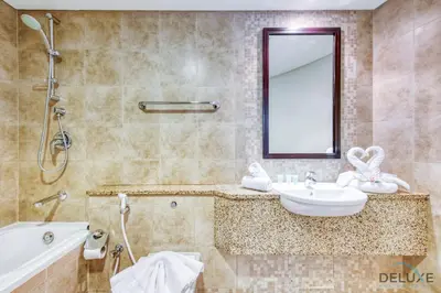 a bathroom with a sink and a tub and a mirror at Tranquil Studio at Sky Gardens DIFC by Deluxe Holiday Homes in Dubai