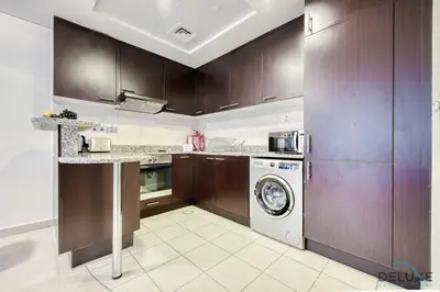 a kitchen with wooden cabinets and a washer and dryer at Radiant Studio at Sky Gardens DIFC by Deluxe Holiday Homes in Dubai