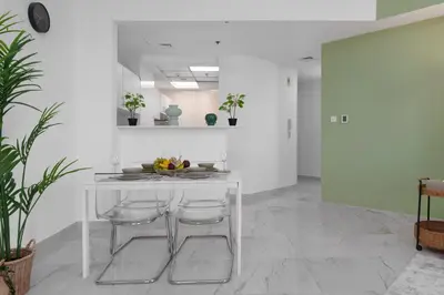 a white kitchen with a table and two stools at Marco Polo - Your luxurious high-floor escape in Dubai Marina in Dubai