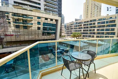a balcony with two chairs and a table and some buildings at Luxury Escapes - Budget Studio with Balcony, Yacht Bay Marina in Dubai