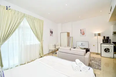 a white bedroom with a bed and a living room at Luxury Escapes - Budget Studio with Balcony, Yacht Bay Marina in Dubai